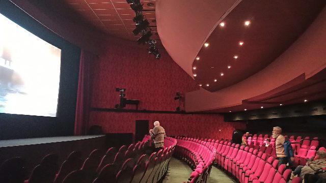 Kinosaal des Cinema Paradiso Baden mit roten Sitzreihen in einem Bogen, links die beleuchtete Leinwand